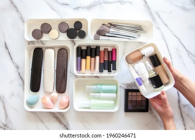 Top View Of Female Visagiste Is Neatly Placing Cosmetic And Vanity Items In MUJI's PP Makeup Storage Boxes With Various Sizes On White Marble Dressing Table. Decluttering And Organization Concept.