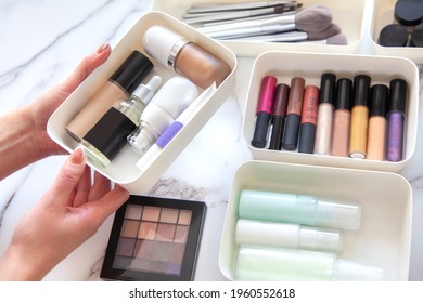 Top View Of Female Visagiste Is Neatly Placing Cosmetic And Vanity Items In MUJI's PP Makeup Storage Boxes With Various Sizes On White Marble Dressing Table. Decluttering And Organization Concept.