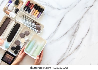 Top View Of Female Visagiste Is Neatly Placing Cosmetic And Vanity Items In MUJI's PP Makeup Storage Boxes With Various Sizes On White Marble Dressing Table. Decluttering And Organization Concept.