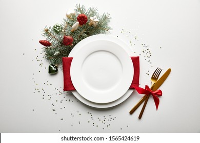 Top View Of Festive Christmas Table Setting On White Background With Decorated Pine Branch And Confetti