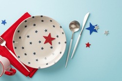 Top View Of Festive Table Arrangement Inspired By Independence Day USA, Featuring Patriotic Elements: Dish, Cup, Cutlery, Napkin, Sparkle Stars, In National Flag Colors. Pastel Blue Backdrop