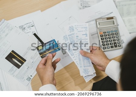 Top view financial owe asian young man sitting suffer, stressed and confused by calculate expense from invoice, credit card bill no money to pay mortgage or loan. Debt, bankrupt or bankrupt people.