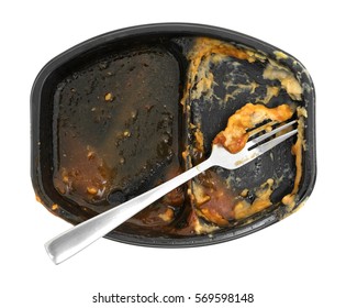 Top View Of A Finished Barbecue And Potato TV Dinner With A Fork In The Tray Isolated On A White Background.