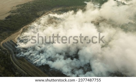 Top view of a fire at a landfill with plastic waste. An environmental disaster, toxic smoke from the fire pollutes the air. The importance of sorting and recycling waste. Let's save the planet.