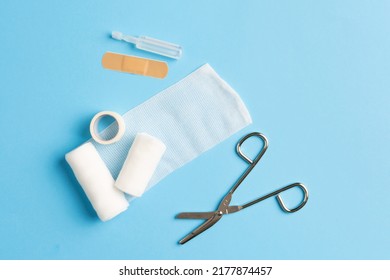 Top View Of First Aid Kit, Bandage, Adhesive Plaster, Tape And Scissors On The Blue Background.