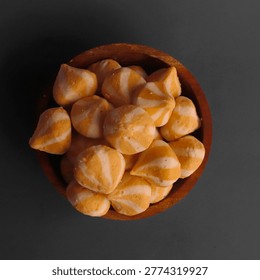 Top view of fish dumpling cheese or orange-striped surimi balls served in a small wooden bowl on a dark background. A popular savory ingredient for steamboat, suki, hotpot, or Indonesian street food seblak. 