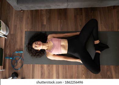 Top view of a fit young woman practicing yoga in the living room and doing a bound angle pose