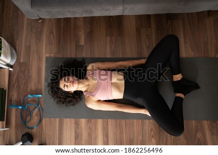 Top view of a fit young woman practicing yoga in the living room and doing a bound angle pose