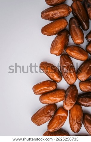 Top view of five dried dates arranged diagonally on a light cream background. Simple organic food layout, perfect for packaging, healthy eating, or clean food concepts.