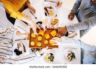 Top view of five multicultural friends sitting at dinning table and having healthy lunch.