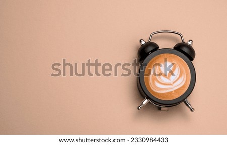 Top view flat lay alarm clock with coffee into it. Beige light brown background copy space. Minimal art coffee collage.