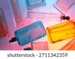 Top view flat lay of assorted perfume bottles on colorful background with vibrant colored liquids arranged on reflective surface