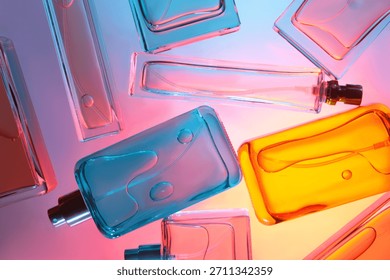 Top view flat lay of assorted perfume bottles on colorful background with vibrant colored liquids arranged on reflective surface