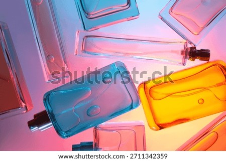 Top view flat lay of assorted perfume bottles on colorful background with vibrant colored liquids arranged on reflective surface