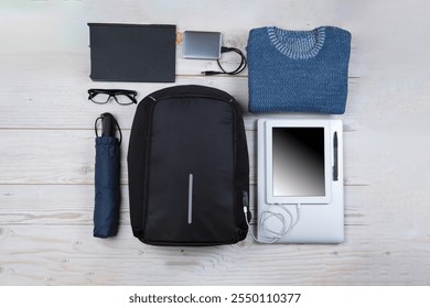 Top View Flat Lay of Backpack With Laptop and Tablet, Mobile Phone With Mouse and Sweater Over Wooden Background. Concept of Travel Life. Horizontal Image - Powered by Shutterstock