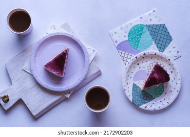 Top View Flat Lay Of Blueberry Cheesecake On Paper Party Plate And Tea Drinks On Purple Paper Cup With Purple Background