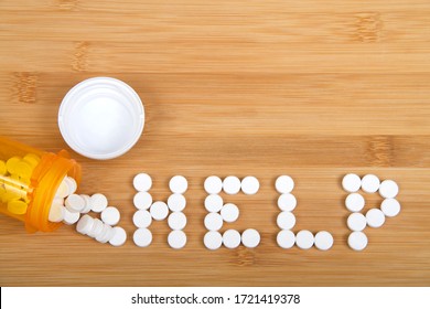 Top View Flat Lay Bottle Of Pain Pills Spilled On Wood Table Spelling The Word HELP. Addiction And Opioid Epidemic Theme Imager With Copy Space.