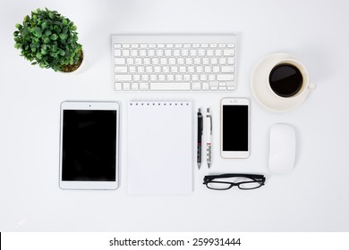 Top view flat lay of business office work space white desk table with a keyboard, mouse, tablet, paper note, coffee and pen