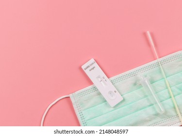 Top View Or Flat Lay Of Covid-19 Negative Test Result Antigen Test Kit (ATK)  With A Nasal Swab And Dropper On Medical Face Mask On  Pink Background With Copy Space. 