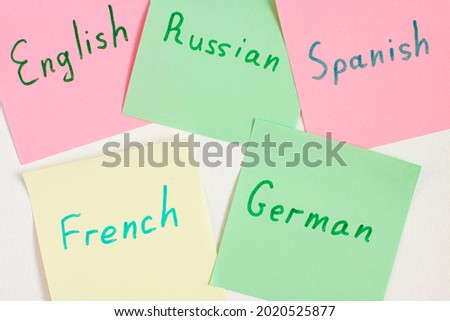 Top view flat lay of different languages which written on the reminder notepaper of different colors. Flashcards and language studies concept concept. German english spanish french and  russian