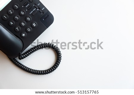 Top view or flat lay of digital voip black telephone on white desk, call center, contact center, customer service, customer support concept background with copy space, selective focus on dial pad