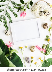 Top view flat lay Easter mockup: white photo frme with quail eggs, daisy flowers and green leaves. Holiday concept. Text space