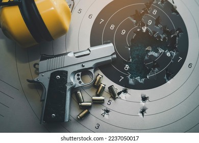 Top view, flat lay of handguns bullets and yellow noise canceling headphones on paper shooting practice target. After shooter practice shooting at theshooting range. Sport shooting concept.