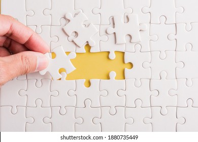 Top view flat lay of hand-holding last piece white paper jigsaw puzzle game last pieces put to place for solve problem complete mission, studio shot on a yellow background, quiz calculation concept - Shutterstock ID 1880735449