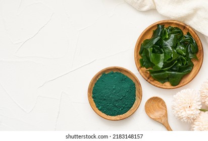 Top View Or Flat Lay Laminaria Or Kelp Seaweed And Spirulina Powder In Wood Plate And Spoon Background. Spirulina Powder With Konbu And Alga Food On White Table Overhead Background.          