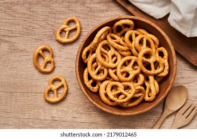 Top View Or Flat Lay Mini Salted Pretzel In A Wooden Bowl With A Spoon And Fork On Wood Table Overhead Background.