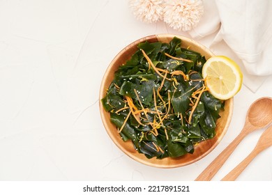 Top View Flat Lay. Overhead Salad Laminaria Kelp Or Wakame Seaweed Salad In Wood Bowl On White Table Background With Copy Space. Salad Laminaria Kelp Or Wakame Seaweed Salad Food