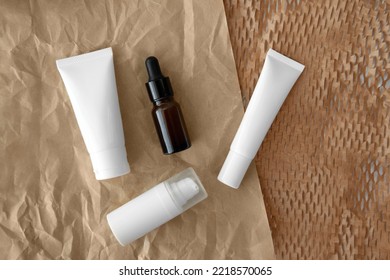 Top view or flat lay  packshot skincare facial white tube bottle blank label product glass serum with Ellwoods Gold Conifer green leaves on brown honeycomb wrap creased paper texture background