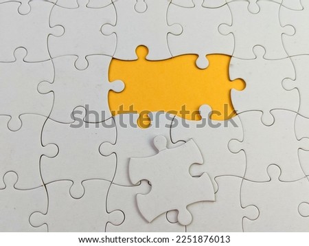 Top view flat lay of paper plain white jigsaw puzzle game texture incomplete or missing piece, studio shot on an orange background, quiz calculation concept
