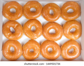 Top View Flat Lay Of Plain Glazed Donuts In A White Box Isolated. One Dozen Donuts. The Original Glazed Donut Has Remained Peoples Favorite Throughout History.