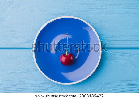 Top view flat lay red cherry on blue plate.