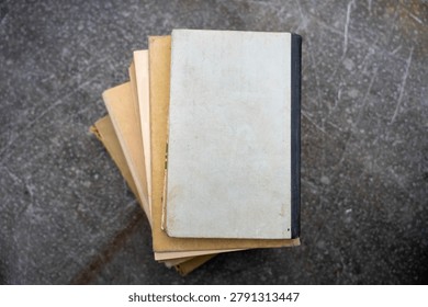 Top view flat lay of small stack of old secondhand books with blank worn covers on grey concrete background, vintage literature stack.