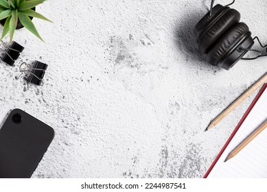 Top view of flat lay table composition with smartphone, pen, notepad and headphone on white gray background