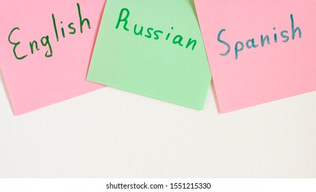 Top view flat lay of two languages english, russian and spanish which written on the reminder notepaper of different colors