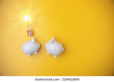 Top view, flat lay two white piggybanks save the money for investment of banking with light bulb on yellow background and copy space. Ideas investments of savings money to the future.