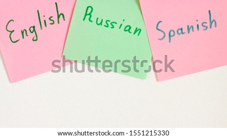 Top view flat lay of two languages english, russian and spanish which written on the reminder notepaper of different colors