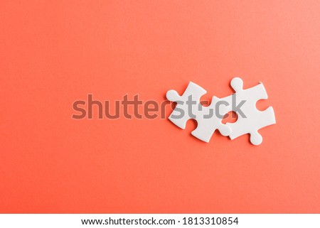 Top view flat lay of two paper plain white jigsaw puzzle game last pieces for solve, studio shot on a red background, quiz calculation concept