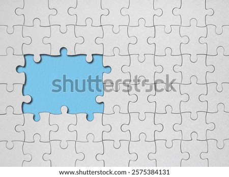 Top view flat lay of white jigsaw puzzle game texture incomplete or missing piece on a yellow, blue and orange background.
