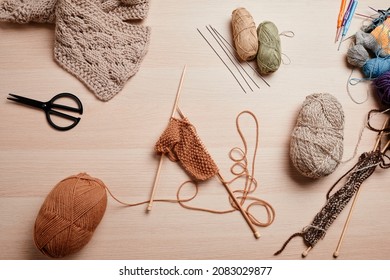 Top view flat lay of wool and knitting supplies on wooden table, copy space