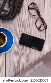 Top view flat lay workesk accesories on white wood. Vertical shot smartphone with glasses and cup of coffee.