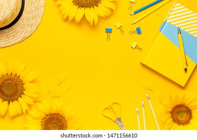 Top view flat lay of workspace desk styled design with sunflowers, straw hat, notebook, diary, pencils, pen scissors on bright yellow background. Autumn or summer Concept. Sunflower natural background
