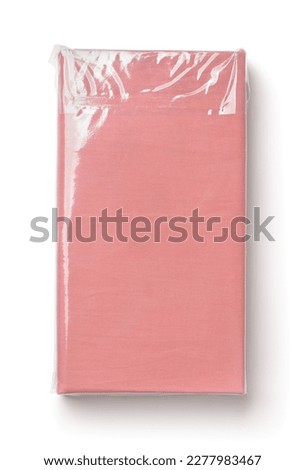 Top view of folded pink cotton bedding sheets in clear plastic bag isolated on white