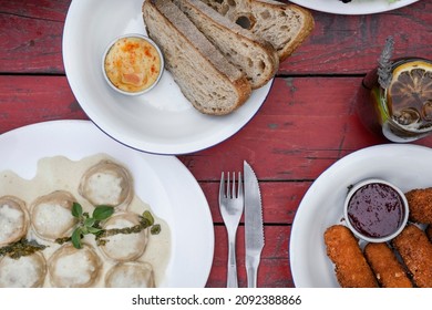 Top View Of The Food On The Restaurant Table. A Dish With Pasta, Sorrentinos, Cream Sauce And Pesto, Sliced Bread With Hummus And Fried Mozzarella Cheese Sticks With Ketchup. 