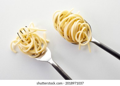 A top view of a fork and spoon with small heaps of spaghetti - Shutterstock ID 2018971037