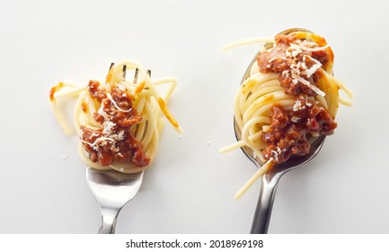 A top view of a fork and spoon with spaghetti bolognese in the light background - Shutterstock ID 2018969198