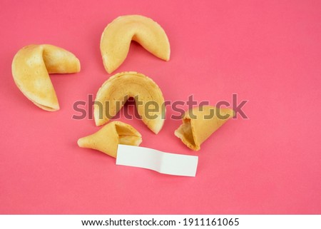 Top view fortune Cookie on a crimson background. Close-up of foreboding broken cookies with white piece of paper with copy space on a dark pink background
